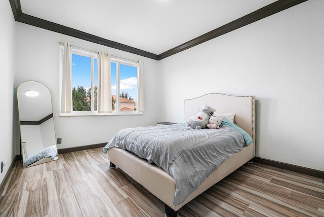 bedroom with ornamental molding and light hardwood / wood-style flooring