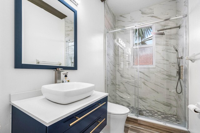 bathroom featuring hardwood / wood-style flooring, toilet, a shower with door, and vanity