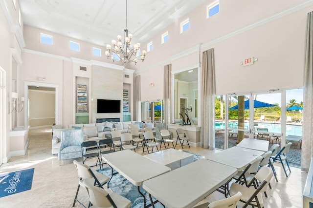 tiled dining room featuring a fireplace, crown molding, a high ceiling, and a notable chandelier