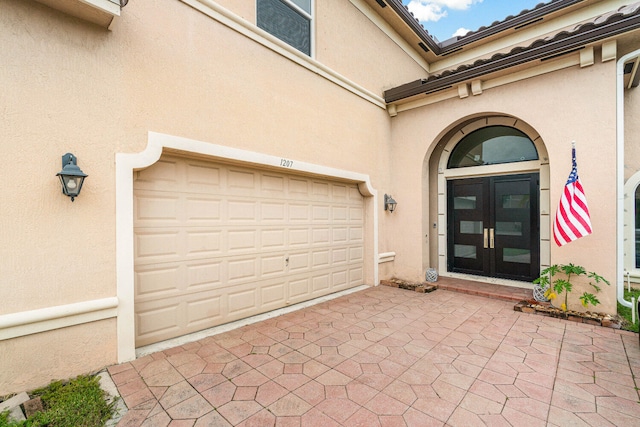 entrance to property featuring a garage and french doors