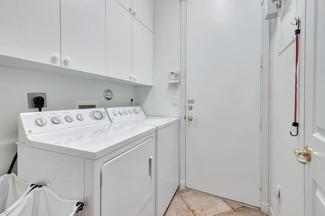 clothes washing area with light tile patterned floors, cabinets, and washer and dryer