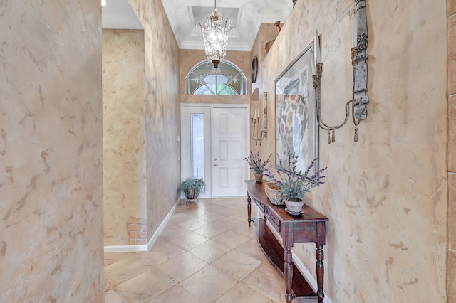 foyer entrance with a towering ceiling, a chandelier, and crown molding