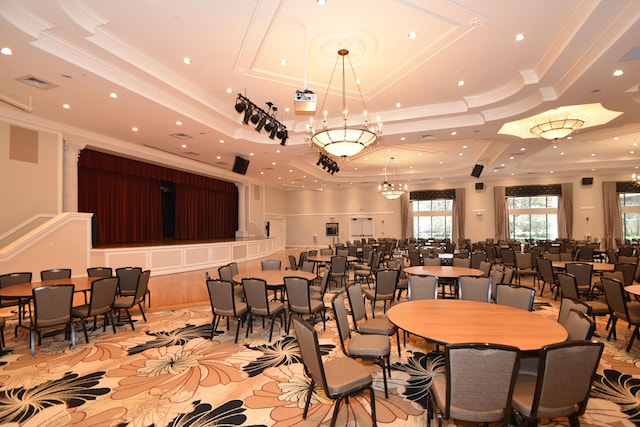 dining space with a raised ceiling, crown molding, and a chandelier