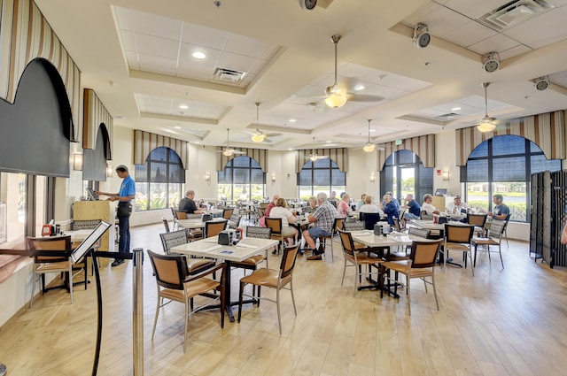 dining space featuring ceiling fan, light wood-type flooring, and coffered ceiling