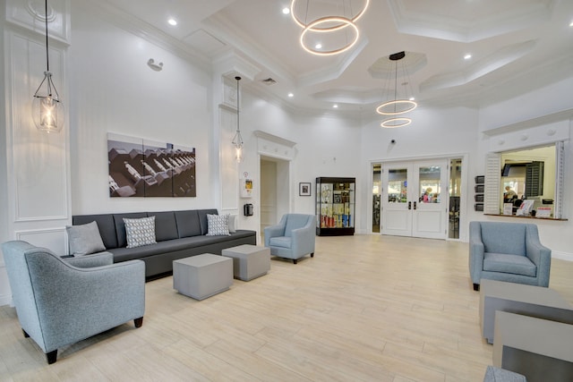 living room featuring light hardwood / wood-style flooring, a high ceiling, coffered ceiling, and crown molding