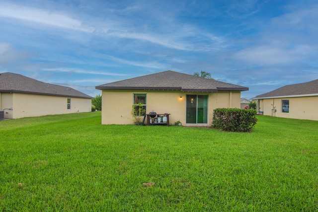 rear view of house featuring a lawn and central AC unit