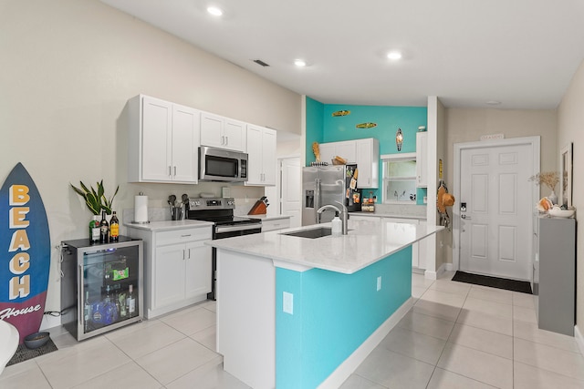 kitchen featuring wine cooler, stainless steel appliances, lofted ceiling, a center island with sink, and sink