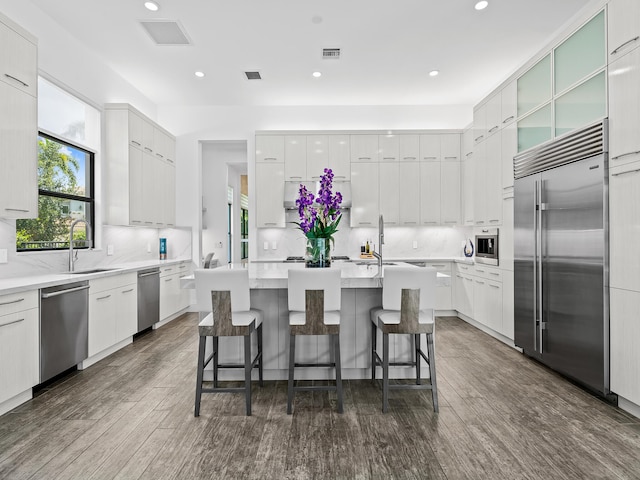 kitchen featuring a kitchen island, white cabinetry, dark wood-type flooring, sink, and stainless steel appliances