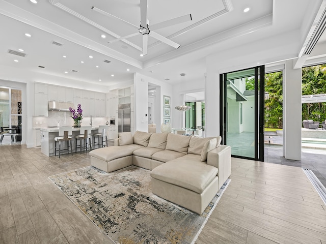 living room featuring ornamental molding, light wood-type flooring, and ceiling fan