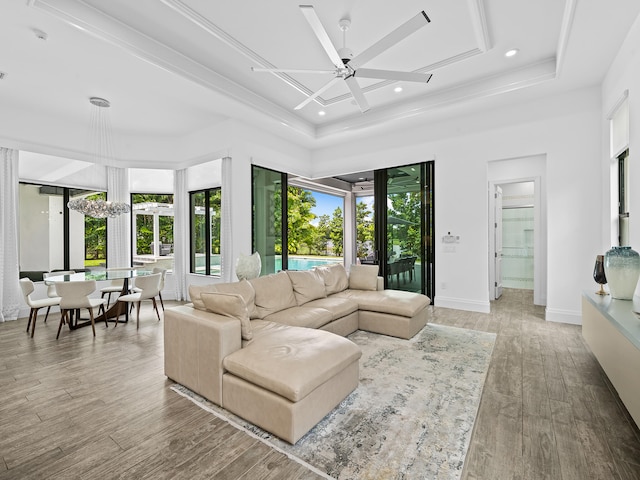 living room featuring a raised ceiling, plenty of natural light, ceiling fan with notable chandelier, and hardwood / wood-style floors