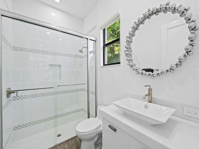 bathroom featuring vanity, toilet, wood-type flooring, and a shower with shower door