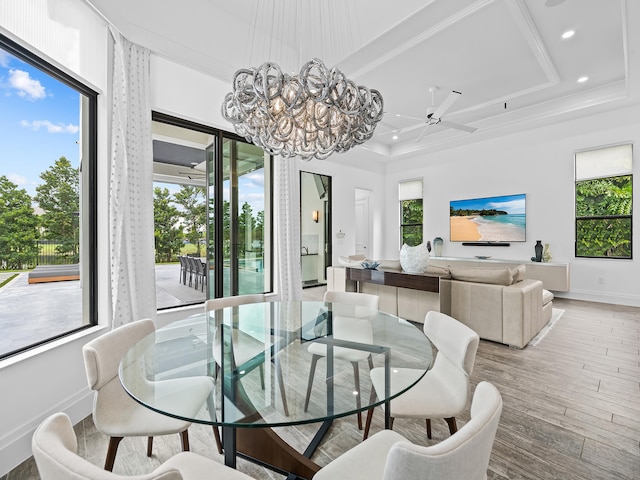 dining area with ornamental molding, ceiling fan with notable chandelier, hardwood / wood-style flooring, and a healthy amount of sunlight