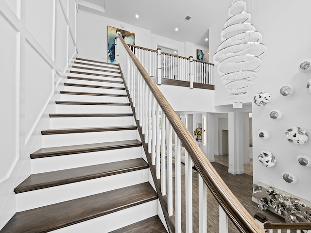 staircase with a notable chandelier and hardwood / wood-style floors