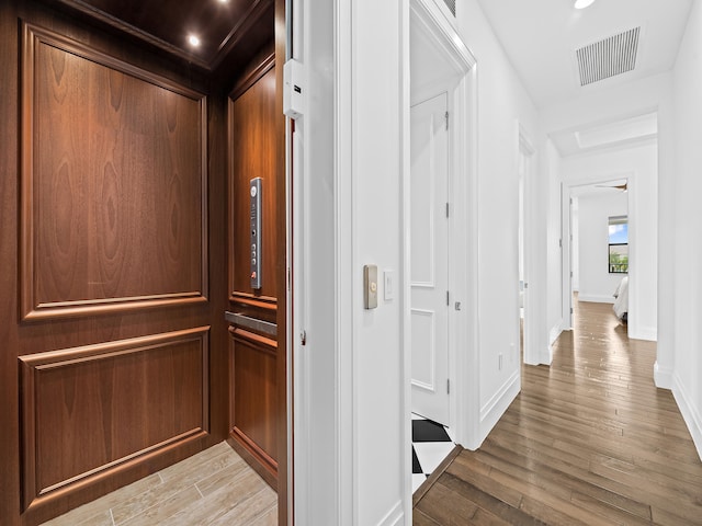 corridor with hardwood / wood-style floors and elevator