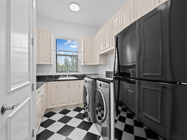 clothes washing area with sink, washing machine and dryer, and cabinets