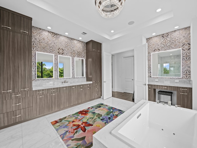 bathroom featuring a bathtub, a notable chandelier, a tray ceiling, and vanity