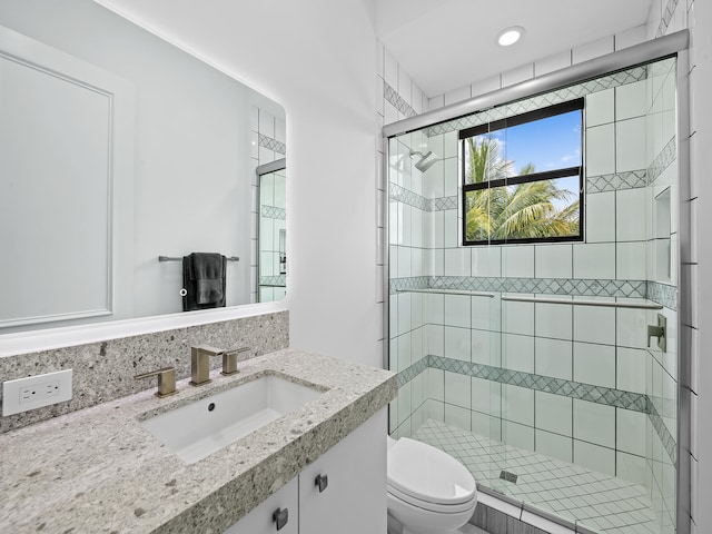 bathroom featuring vanity, a shower with shower door, and toilet