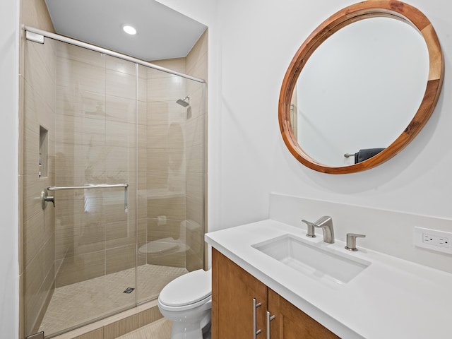 bathroom featuring vanity, a shower with shower door, and toilet