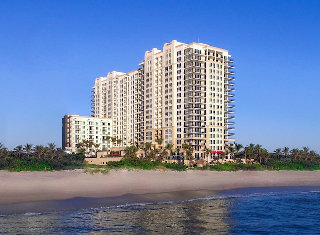 view of building exterior featuring a water view and a beach view