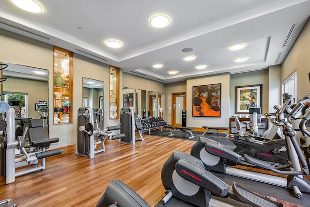 gym with a tray ceiling and hardwood / wood-style flooring