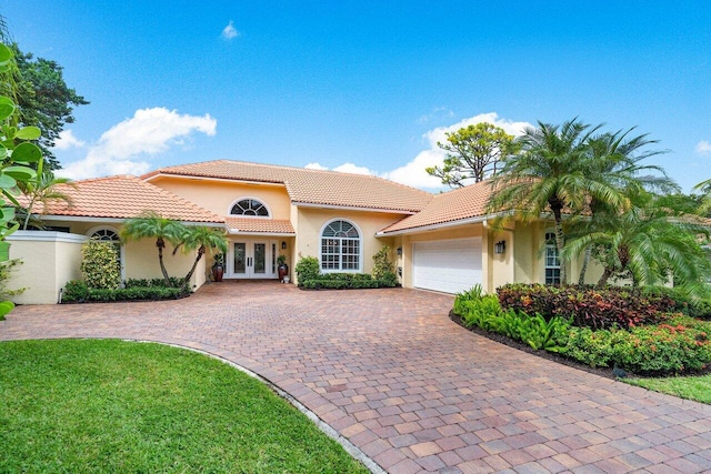 mediterranean / spanish house with a garage and french doors