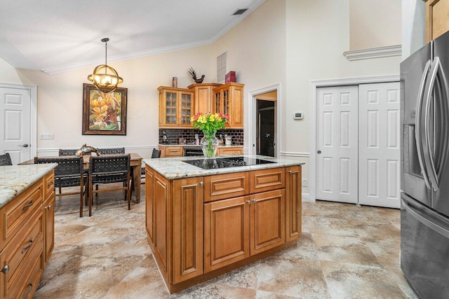 kitchen with stainless steel refrigerator with ice dispenser, black electric cooktop, light stone counters, and decorative light fixtures