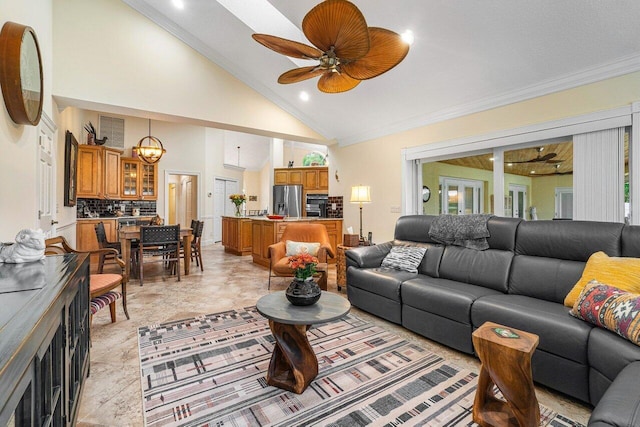 living room with ceiling fan with notable chandelier, high vaulted ceiling, and crown molding