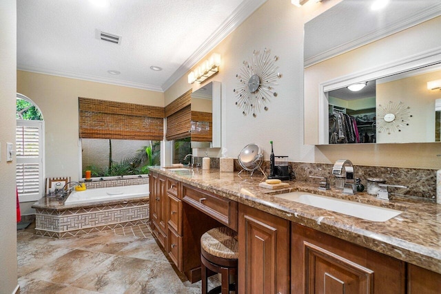 bathroom featuring tiled tub, crown molding, vanity, and a textured ceiling