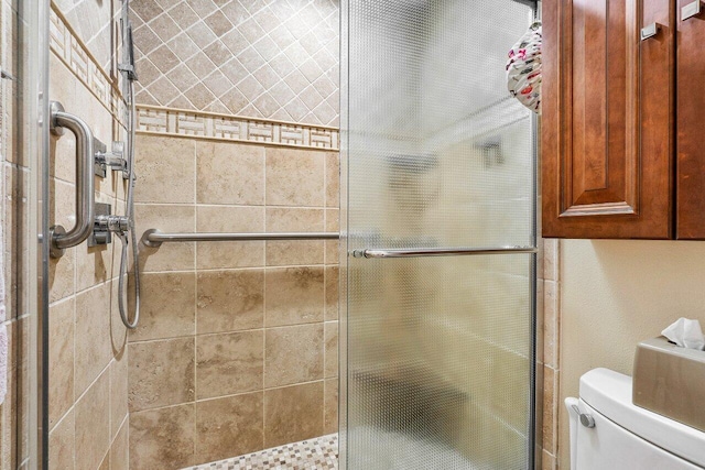 bathroom featuring toilet and a shower with door