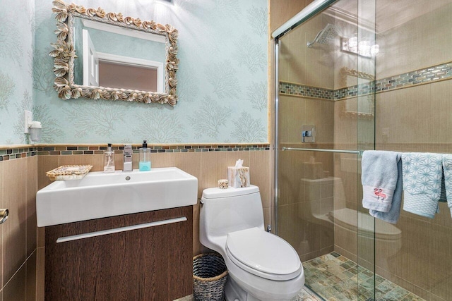 bathroom featuring vanity, a shower with shower door, tile walls, and toilet