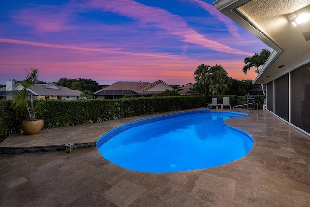 pool at dusk with a patio area