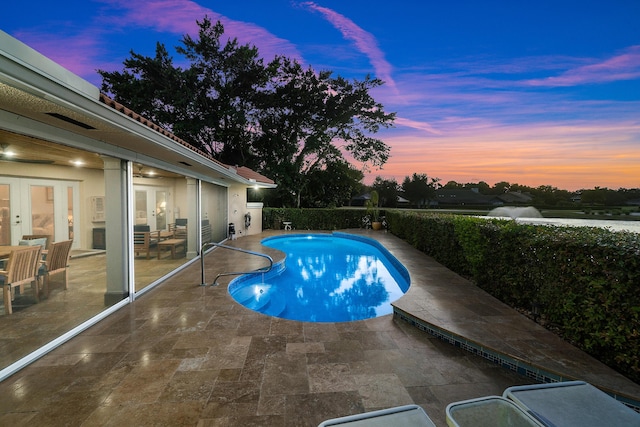 pool at dusk with a patio and french doors