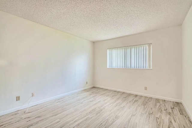 spare room with light hardwood / wood-style floors and a textured ceiling