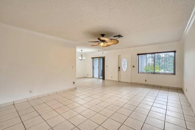 tiled empty room with ceiling fan with notable chandelier and a textured ceiling