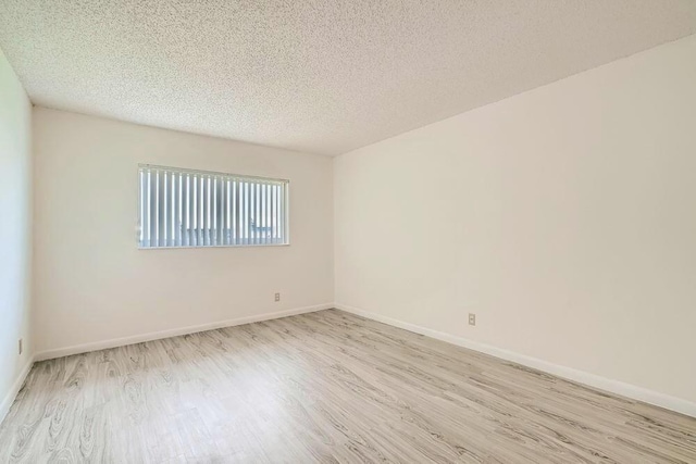 unfurnished room with light hardwood / wood-style flooring and a textured ceiling