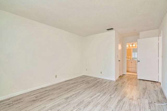 empty room with light hardwood / wood-style floors and a textured ceiling