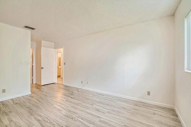 empty room featuring a textured ceiling and light hardwood / wood-style flooring