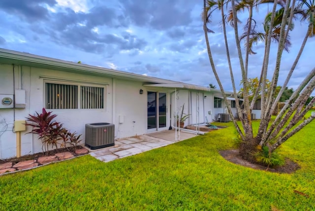 back of property featuring central AC unit, a lawn, and a patio