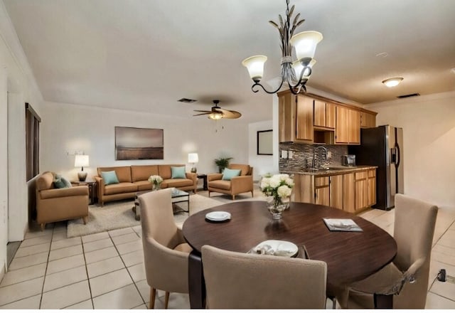 tiled dining room with sink, ceiling fan with notable chandelier, and ornamental molding