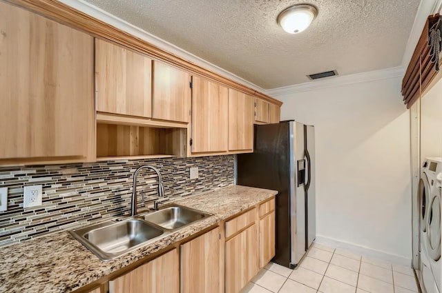 kitchen featuring washing machine and dryer, light brown cabinetry, sink, ornamental molding, and light tile patterned floors