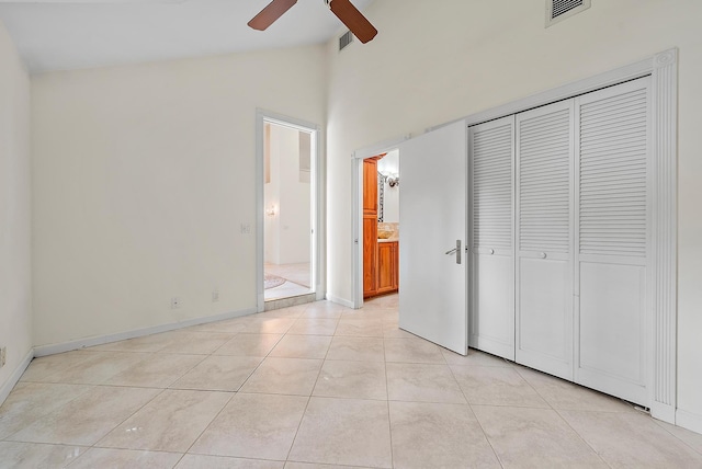 unfurnished bedroom with light tile patterned floors, lofted ceiling, ceiling fan, and a closet