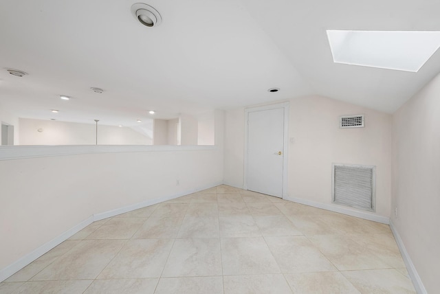 additional living space with vaulted ceiling with skylight and light tile patterned floors