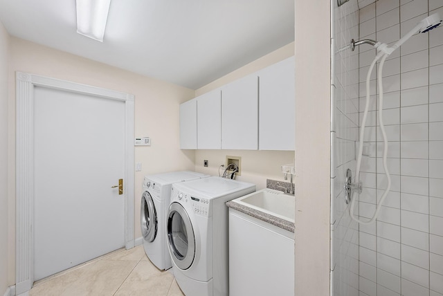 laundry area featuring cabinets, light tile patterned floors, and washer and clothes dryer