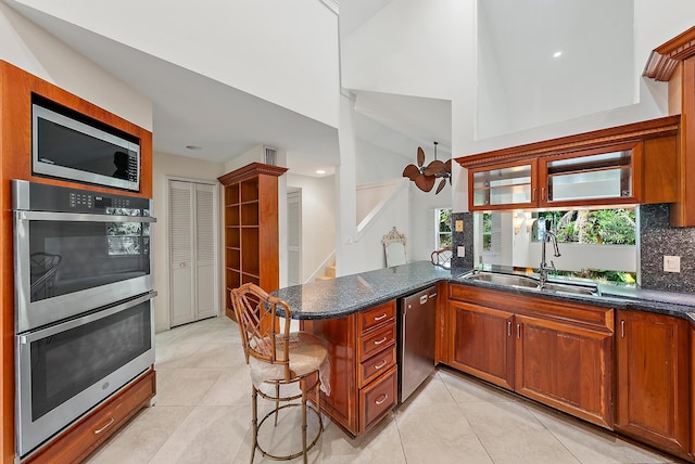 kitchen with appliances with stainless steel finishes, decorative backsplash, kitchen peninsula, a breakfast bar area, and sink