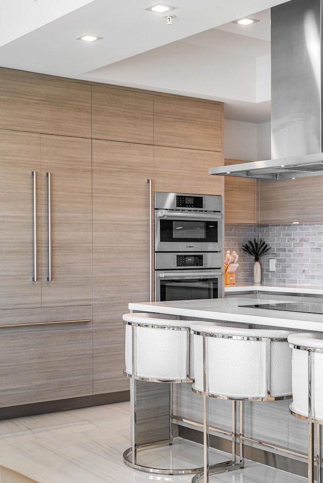 kitchen featuring stainless steel double oven, decorative backsplash, wall chimney exhaust hood, and black electric stovetop