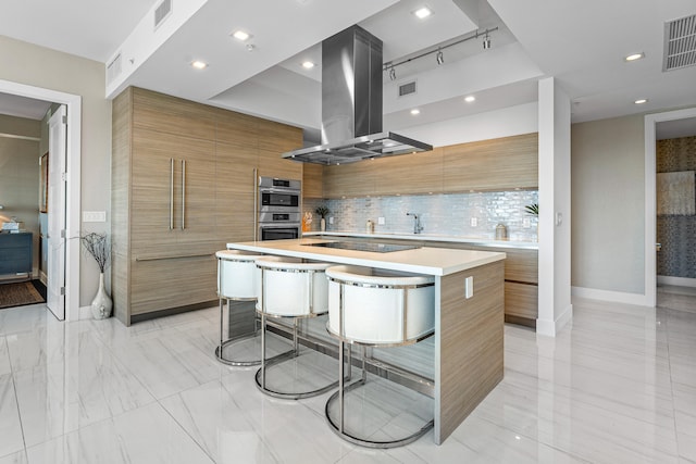 kitchen featuring a large island, tasteful backsplash, a kitchen breakfast bar, exhaust hood, and black electric cooktop