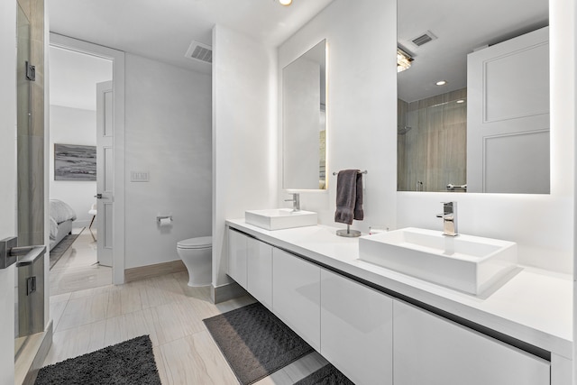 bathroom with tile patterned floors, tiled shower, vanity, and toilet