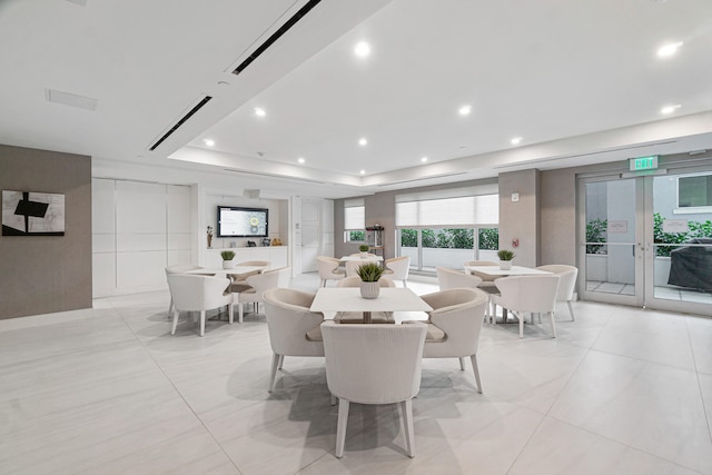 dining area with a raised ceiling and light tile patterned flooring