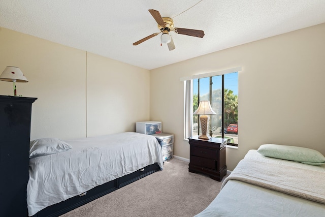 bedroom featuring ceiling fan, light colored carpet, and a textured ceiling