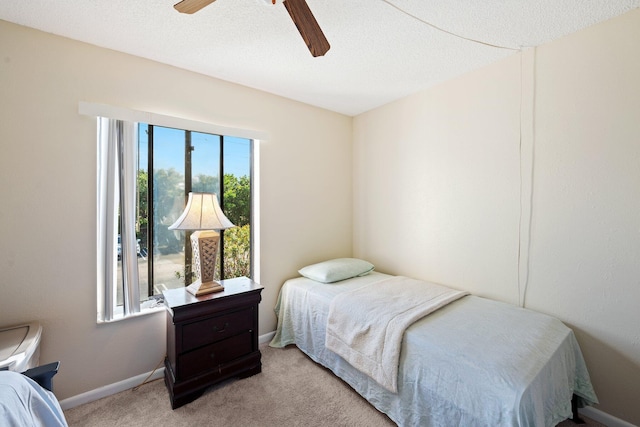 carpeted bedroom with ceiling fan and a textured ceiling